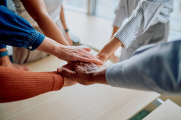 Diverse business team stacking hands together, symbolizing unity, collaboration, and shared success in a corporate environment