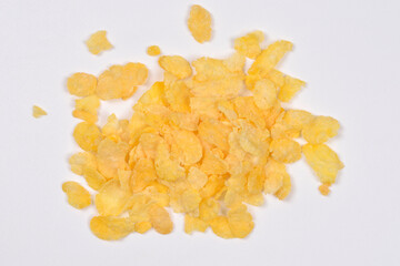 A small pile of golden corn flakes is centrally placed on a plain white background