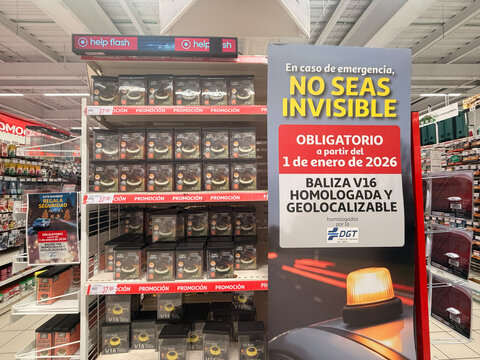 Alicante, Spain - December 11, 2025: Emergency vehicle safety products displayed in a retail store, featuring V16 geolocalizable beacons and promotional signage for visibility awareness