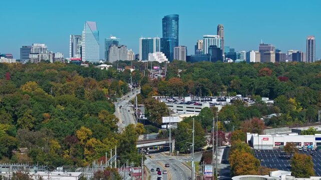 Buckhead, Atlanta, Georgia, United States of America - A Long Road Stretches through Dense Autumn Trees Toward a Modern High-rise Skyline - Aerial Drone Shot