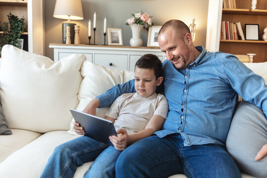 Father and son bonding and using digital tablet at home. Single dad and his son using digital tablet at home. - Powered by Adobe