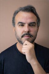 Headshot of mid adult man with gray hair and gray beard, posing with hand on chin. Vertical studio portrait ideal for male topics, planning and thinking themes, and problem-solving content.