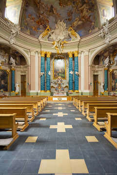 View of a sanctuary interior with rows of wooden pews, a teal backdrop, and an ornate ceiling fresco, Muenster, North Rhine-Westphalia, Germany.