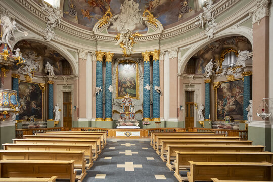 View of Clemenskirche baroque church interior with rows of wooden pews leading to a gilded altar beneath a frescoed dome, Muenster, North Rhine-Westphalia, Germany.