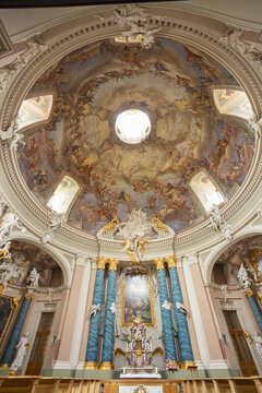 View of Clemenskirche baroque church interior with rows of wooden pews leading to a gilded altar beneath a frescoed dome, Muenster, North Rhine-Westphalia, Germany.