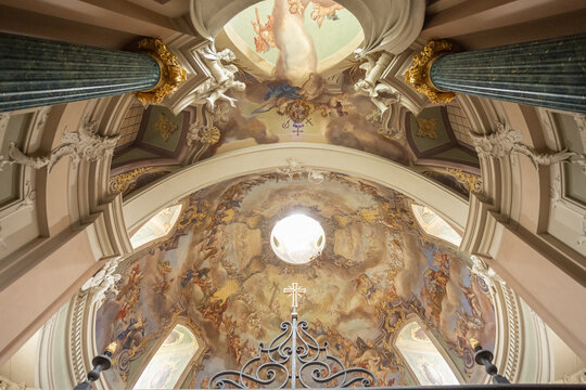 View of Clemenskirche baroque church interior with rows of wooden pews leading to a gilded altar beneath a frescoed dome, Muenster, North Rhine-Westphalia, Germany.