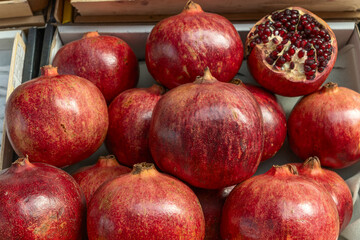 Open pomegranate with red seeds surrounded by whole fruits. Pomegranates in rustic basket showcasing vibrant colors juicy textures and organic produce for culinary.