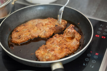 Sizzling Supper Creation Two pork chops frying in a pan on a stove, a fork checks for doneness
