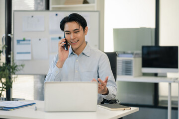 Businessman using laptop computer and smartphone in office. Happy man, entrepreneur, small business owner working online.