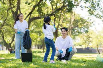 Asian family collects plastic bottles into black bags at a park on the weekend.