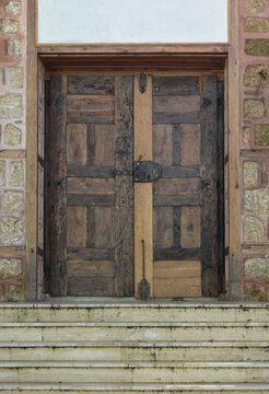 View of a weathered wooden door with iron accents stands guard, set against a textured stone facade and steps, its aged beauty a silent sentinel, Karabuk, Karabuk, Turkey.