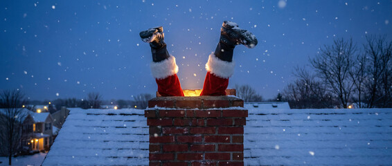 Santa stuck in chimney feet first on snowy rooftop during evening snowfall