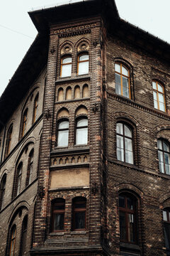 View of a historic brown brick building featuring arched windows and intricate architectural details, captured on a cloudy day, Budapest, Hungary.