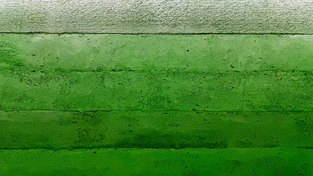 Close-up of a modern, abstract rammed earth wall in green color tone showcasing horizontal layers, natural green tones, and a subtly textured, sustainable building surface.