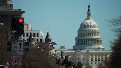 Red traffic lights are visible in front of the US Capitol building in Washington DC on a clear day with blue sky.
