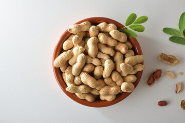 Heap of peanuts in clay bowl with leaves in the center