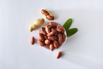 Peeled peanuts in glass bowl isolated on table top view