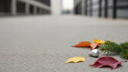 Colorful autumn leaves and a silver ornament on pavement  