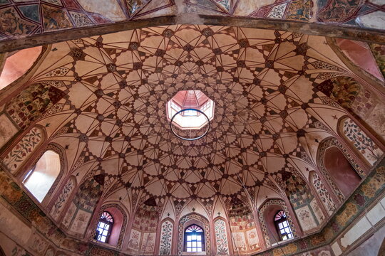 View of a dome with intricate geometric patterns and a central oculus casting light into the historic Shahi Hammam, Lahore, Lahore, Pakistan.