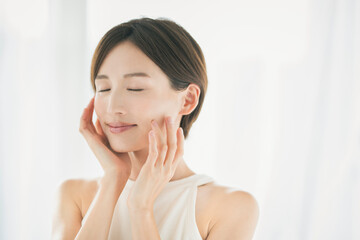 顔を触っている笑顔の若い女性