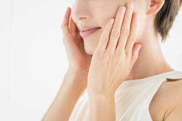 顔を触っている笑顔の若い女性