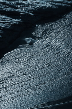 View of textured rock formations carved by time and elements, showcasing a rugged landscape with shadows and light creating depth, Ticino, Bedretto, Switzerland.