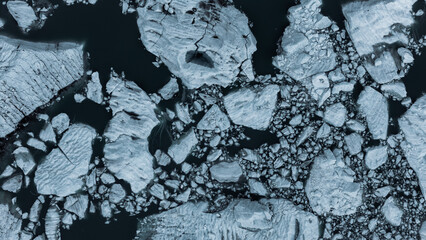 View of icy fragments drift in dark waters, a mosaic of whites and blues creating a stark, cold landscape, Bedretto, Ticino, Switzerland.