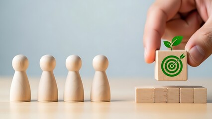 A hand placing a wooden block with a green target and a small plant on top next to a row of people