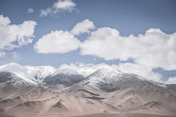 Landscape in the Pamir Mountains of Tajikistan with snow, glaciers, and cliffs, a panorama of mountains in cloudy weather for the background, nature in the Tien Shan highlands, landscape background