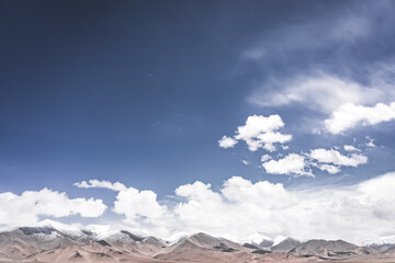 Landscape in the Pamir Mountains of Tajikistan with snow, glaciers, and cliffs, a panorama of mountains in cloudy weather for the background, nature in the Tien Shan highlands, landscape background