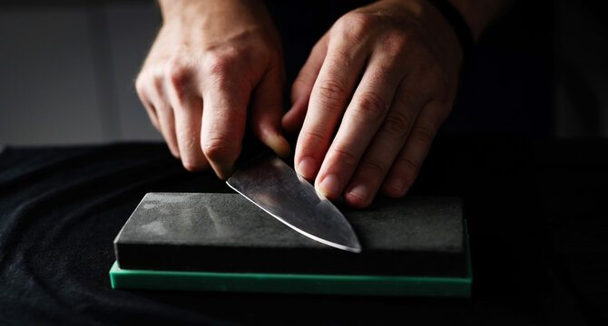 Male Hands Sharpening Kitchen Knife With Whetstone