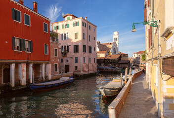 Traditional buildings with reflections along narrow canal in Venice Italy on a sunny day