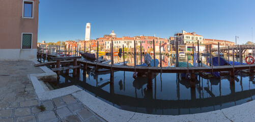 View of a canal with boats and colorful buildings in Venice, Italy under a clear sky