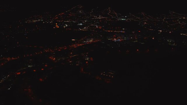 Aerial flyover of Funchal and Madeira highlands shows orange streetlights, winding illuminated roads, ridgelines, and hints of Miradouros and coast beacons.