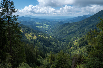 Fototapeta premium Scenic overlook of a lush green valley with rolling mountains and a cloudy sky