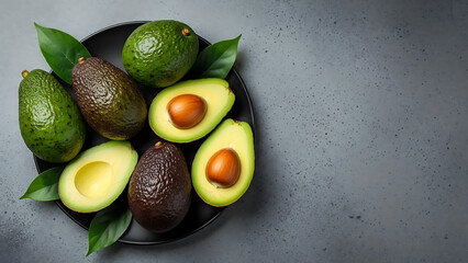 Ripe Avocados on a Dark Plate, Freshly Cut and Whole, with Green Leaves