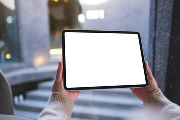Mockup image of a woman holding digital tablet with blank white desktop screen in cafe