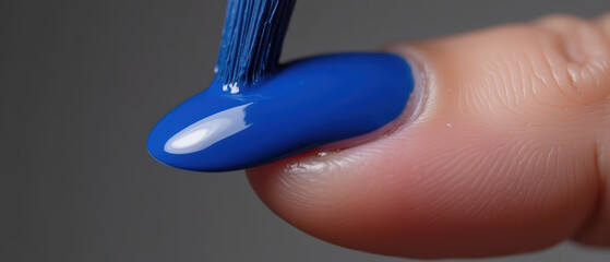 Close up view of finger with blue nail polish being applied, showcasing glossy texture and vibrant color. image captures artistry of nail care