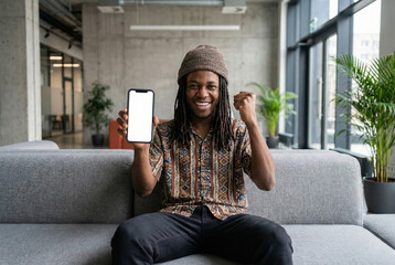 young black man joyfully celebrating successful app release in modern office environment