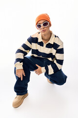 Stylish Gen Z teenager expresses fashion sense in striped polo and vibrant orange hat