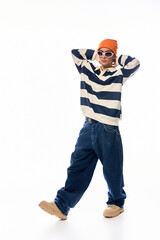 Stylish teenager showcases Gen Z fashion in a striped polo and vibrant orange hat