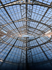 Symmetrical reflection of glass ceiling with steel trusses in polished surface, industrial architectural design with sky view and grid pattern