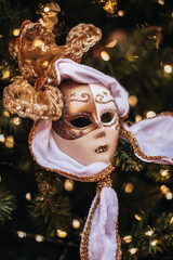 Traditional gold white theatrical mask hanging on a Christmas tree, unique interesting New Year decor, gifts and souvenirs