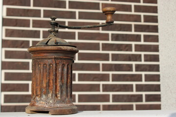 Fototapeta premium Old coffee grinder on a shelf against a brick wall in a rustic setting during the afternoon