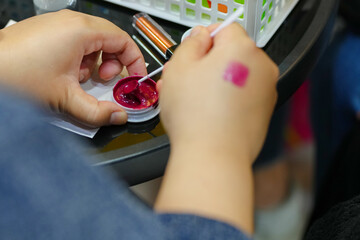 close-up of a woman's hand testing lipstick swatches