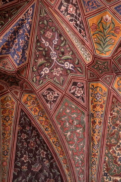 View of an ornate ceiling adorned with intricate floral patterns and geometric designs in rich, contrasting colors, Lahore, Punjab, Pakistan.