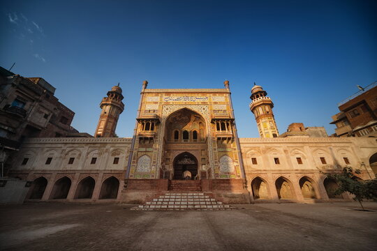 View of an ornate, historical building with intricate details stands proudly against a clear blue sky, its sandstone walls glowing warmly, Lahore, Punjab, Pakistan.