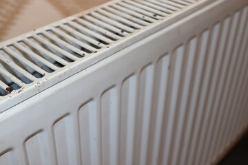 Dust collects on a white radiator in a room showing signs of wear and age during the day