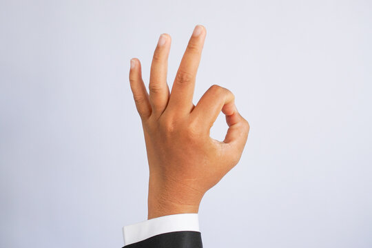 Business hand in a suit making an OK gesture, isolated on white background.