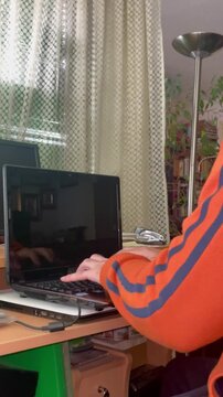 Escribiendo y tecleando en ordenador port&aacute;til un correo email y trabajando desde casa en escritorio de oficina